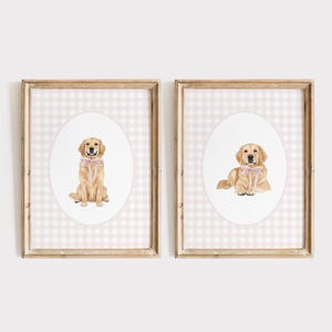 May include: Two framed prints featuring watercolor illustrations of Golden Retrievers. Each dog wears a pink bow. The background is a pink and white gingham pattern. The frames are a light brown color.