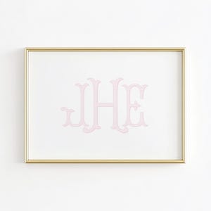 May include: A framed print featuring the monogram "JHE" in a light pink, striped design. The letters are displayed on a white background, encased in a gold-colored frame. The artwork is a decorative piece.
