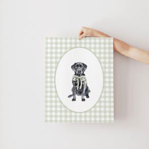 May include: A black Labrador Retriever wearing a green bow sits in a white oval on a green and white gingham background.