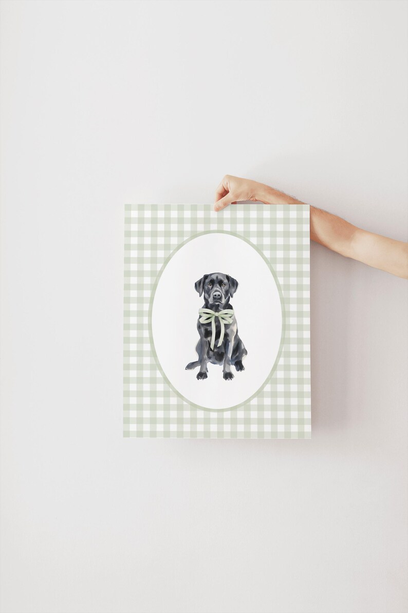 May include: A black Labrador Retriever wearing a green bow sits in a white oval on a green and white gingham background.