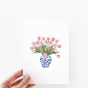May include: A watercolor painting of a bouquet of pink tulips in a blue and white porcelain vase.