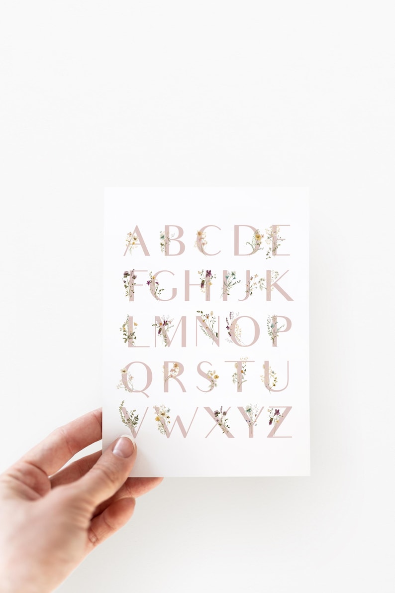 May include: A white card with the alphabet printed in pink letters. Each letter is decorated with a floral design in shades of pink, yellow, and brown.