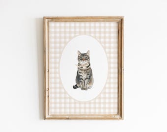 May include: A framed print of a tabby cat sitting in a white oval on a beige and white gingham background.