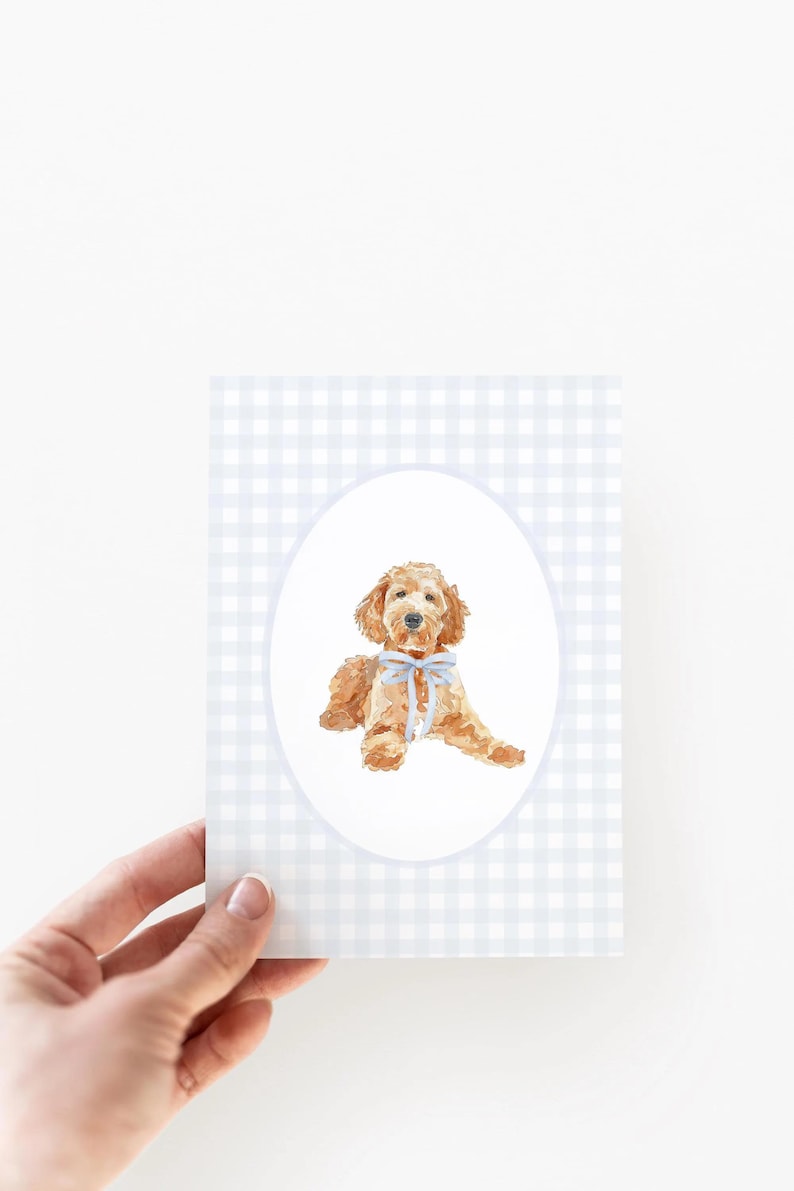 Pode incluir: Ilustra&ccedil;&atilde;o em aquarela de um c&atilde;o golden doodle com um la&ccedil;o azul claro, emoldurada em um oval. O fundo apresenta um padr&atilde;o xadrez vichy azul claro e branco. A imagem est&aacute; em um cart&atilde;o.