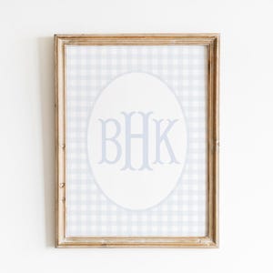 May include: A framed print with a light blue and white gingham pattern. The print features a white oval with the monogram "BHK" in light blue.