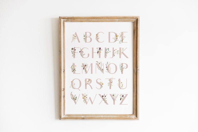 May include: A framed print of the alphabet with each letter decorated with floral illustrations in shades of pink, yellow, and white.