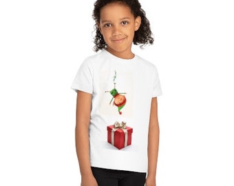 May include: A white t-shirt featuring a green and red cartoon character dangling from a string above a red gift box with a white bow.