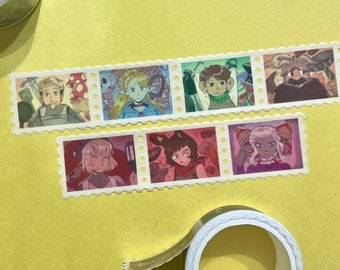 Puede incluir: Cinta adhesiva washi con imágenes ilustradas que se asemejan a sellos postales. Los sellos representan varios personajes en un estilo artístico y colorido. La cinta está sobre una superficie amarilla, con un rollo de cinta visible.