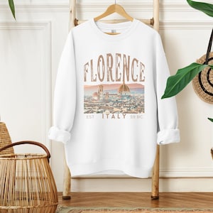 May include: White sweatshirt with a graphic print of the Florence skyline, featuring the text "FLORENCE EST ITALY 59 BC".