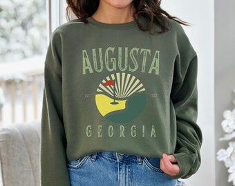May include: A green sweatshirt with a vintage-style graphic of a golf course and the text "Augusta, Georgia, Est. 1937".