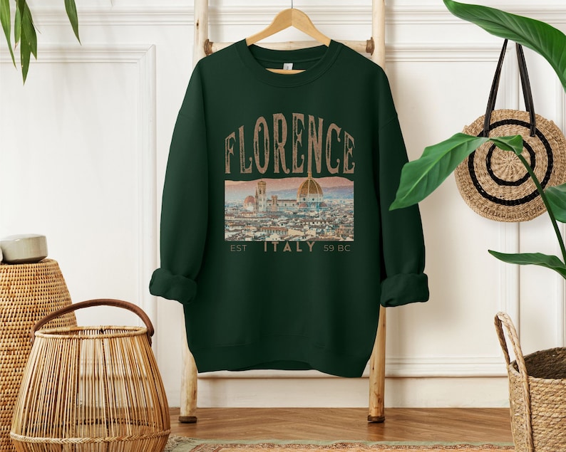 May include: A dark green sweatshirt with a vintage-style graphic of the Florence skyline and the text "FLORENCE EST. ITALY 59 BC".