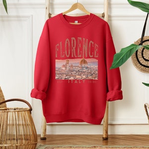 May include: Red sweatshirt with a graphic print of the Florence skyline and the text "FLORENCE EST. ITALY 59 BC".