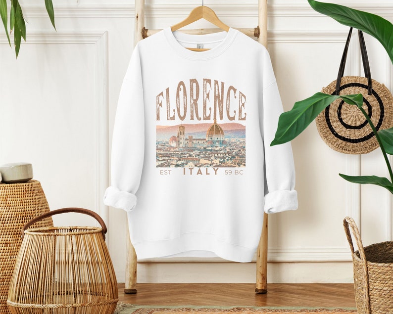 May include: White sweatshirt with a graphic print of the Florence skyline, featuring the text "FLORENCE EST ITALY 59 BC".