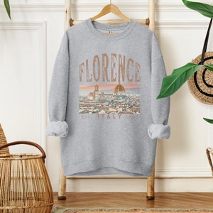 May include: A gray sweatshirt with a graphic print of the Florence skyline and the text "Florence Est. Italy Sp. 1970".