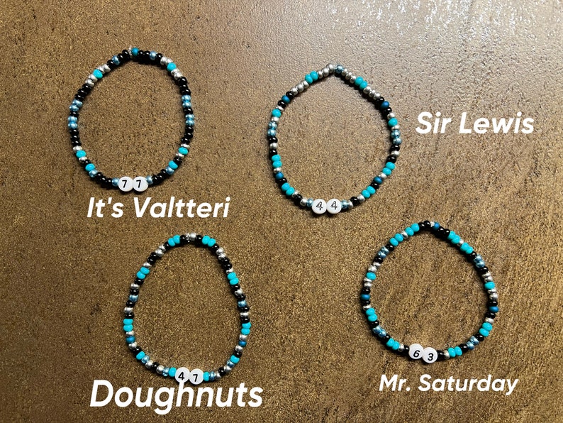 K&ouml;nnte beinhalten: Vier Perlenarmb&auml;nder mit verschiedenen Perlenfarben und Zahlen. Die Armb&auml;nder sind mit "It's Valtteri", "Sir Lewis", "Doughnuts" und "Mr. Saturday" beschriftet.