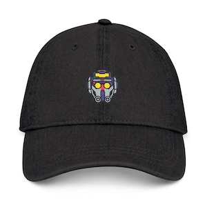 May include: Black baseball cap with a robot face embroidered on the front. The robot face is gray, yellow, and red. The cap has a curved brim and an adjustable strap at the back.