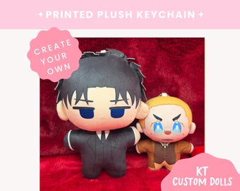 May include: Two printed plush keychains featuring stylized characters. The larger doll has black hair and a black suit. The smaller doll has blonde hair, glasses, and a brown vest. Text on the image reads: PRINTED PLUSH KEYCHAIN, CREATE YOUR OWN, KT CUSTOM DOLLS.