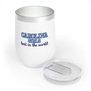 May include: White insulated tumbler with a silver rim and a clear lid. The tumbler has the text "CAROLINA GIRLS best in the world" in blue lettering. The lid is clear with a silver clasp.