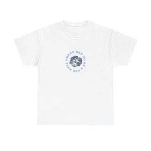 Könnte beinhalten: Weißes T-Shirt mit einem hellblauen kreisförmigen Design. Das Design enthält den Text "UNC" und "HEEL GREAT DAY TO BE A TAR" um eine Grafik herum. Das Shirt ist aus weichem Material.