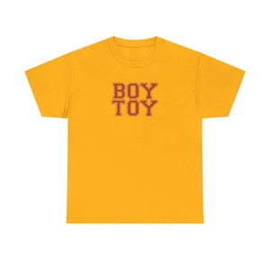 May include: A yellow t-shirt with the words "BOY TOY" printed in red.