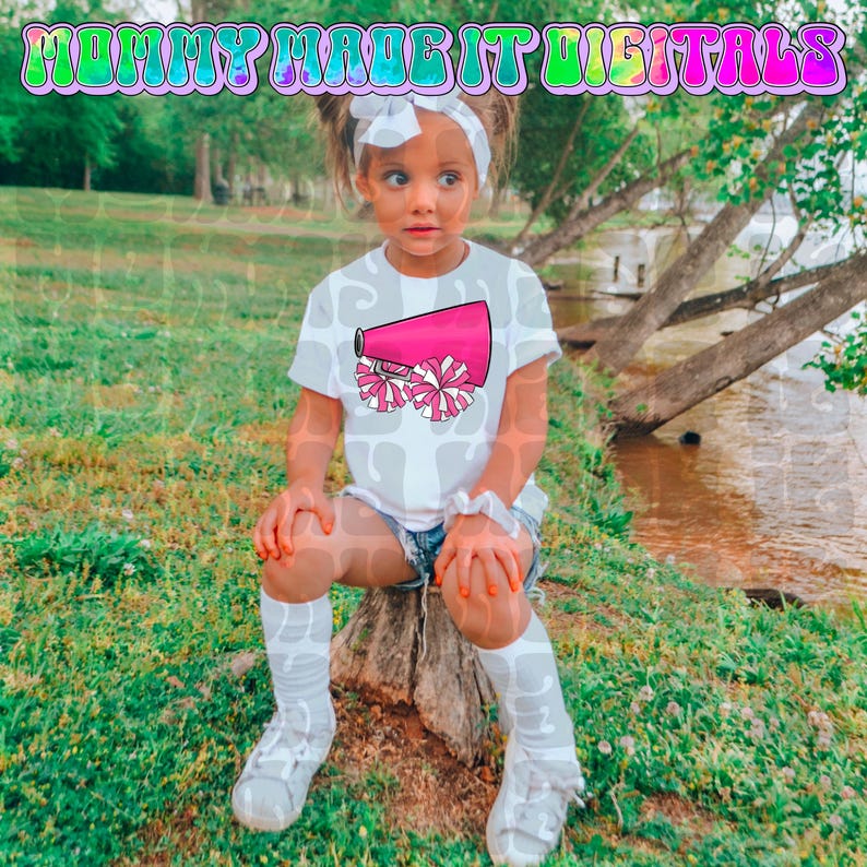 Puede incluir: Una ni&ntilde;a lleva una camiseta blanca con un dise&ntilde;o de meg&aacute;fono y pompones rosas. La camiseta se combina con pantalones cortos de mezclilla, calcetines blancos y zapatillas deportivas. El texto "MOMMY MADE IT DIGITALS" est&aacute; incluido.