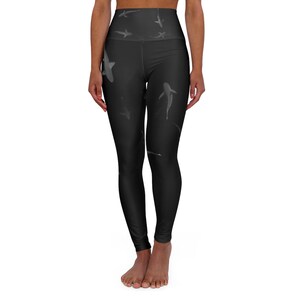 May include: Black high-waisted yoga leggings with a repeating pattern of white sharks. The leggings are made of a stretchy, comfortable fabric.