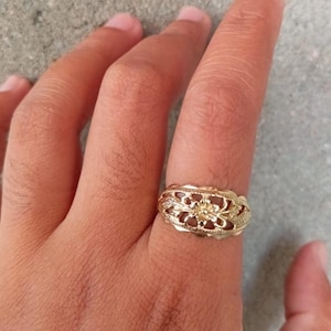 May include: A gold filigree ring with a floral design.