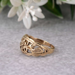 May include: A gold ring with a floral design. The ring is made of a delicate metal and features a flower with leaves.
