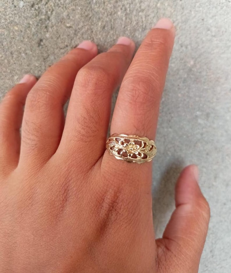 May include: A gold filigree ring with a floral design.