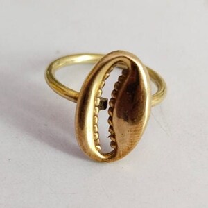 Op de afbeelding: Een gouden ring met een schelpvormig ontwerp. De ring is gemaakt van metaal en heeft een eenvoudige band.
