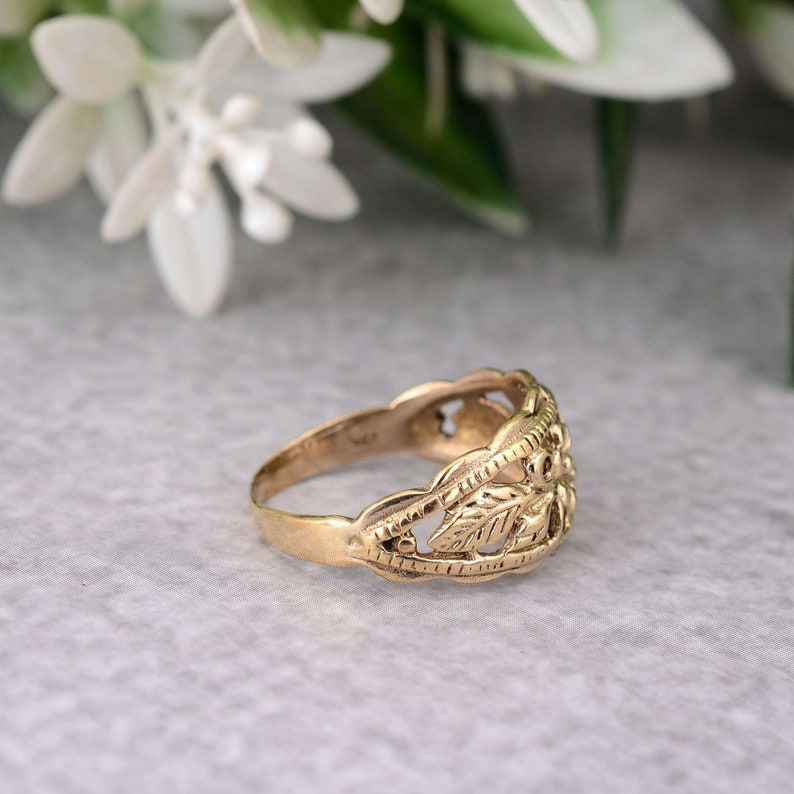 May include: A gold ring with a delicate, intricate design featuring leaves and swirls. The ring is made of a smooth, polished metal and has a classic, elegant style.
