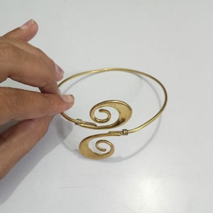 Pu&ograve; includere: Un braccialetto in metallo dorato con un design unico che presenta due forme a spirale. Il braccialetto &egrave; aperto e regolabile.