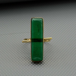Könnte beinhalten: Ein goldener Ring mit einem rechteckigen grünen Edelstein.