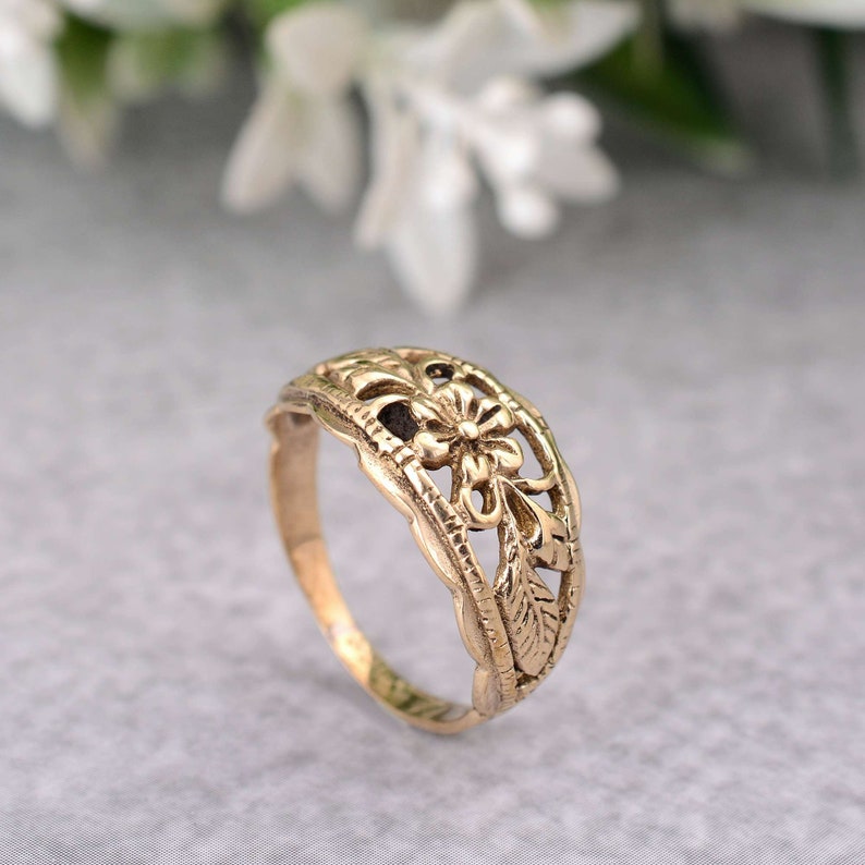 May include: A gold-toned ring with a delicate floral design. The ring is made of a thin band with a cutout flower and leaves.