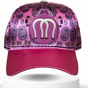 Könnte beinhalten: Rosa Baseballkappe mit Paisley-Muster und einem rosa gestickten Patch mit drei weißen Hufeisen. Die Kappe hat einen gebogenen Schirm und ein Netzrücken.