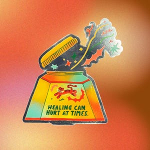 May include: A colorful sticker featuring a jar with an open lid. The jar is yellow, orange, and teal, with a cartoon tiger and the text "HEALING CAN HURT AT TIMES." Stars and other shapes emanate from the jar.