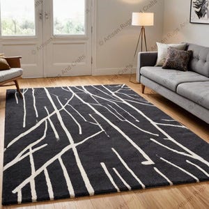 May include: A black and white area rug with a modern abstract design featuring white lines resembling branches on a dark gray background.