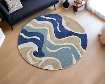 May include: A round rug with a blue, beige, and white abstract wave pattern. The rug is made of a soft, plush material.