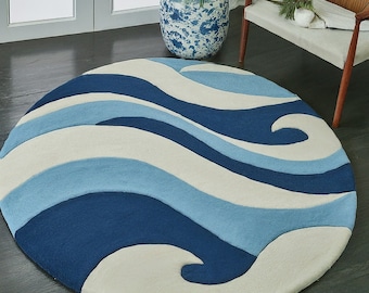 May include: A round, cream-colored rug with a blue and light blue wave pattern. The rug has a soft, plush texture.