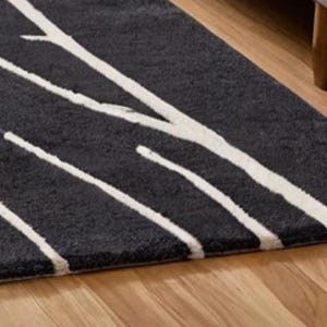 May include: A black and white area rug with a modern abstract design. The rug has a thick pile and a soft texture.