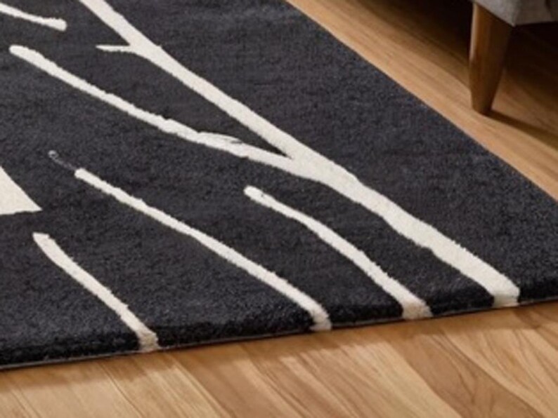 May include: A black and white area rug with a modern abstract design. The rug has a thick pile and a soft texture.