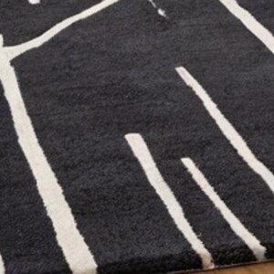 May include: Black and white area rug with a geometric pattern. The rug has a soft, plush texture.