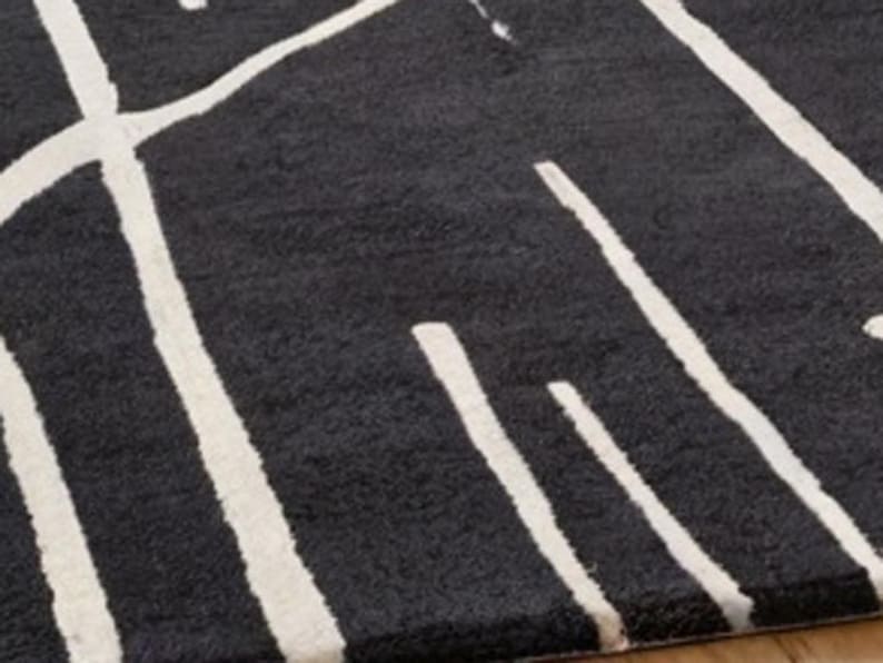 May include: Black and white area rug with a geometric pattern. The rug has a soft, plush texture.