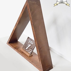 May include: A triangular wooden shelf with a small wooden sign that says "Table 1" on it. The shelf is made of dark brown wood and has a rustic look.