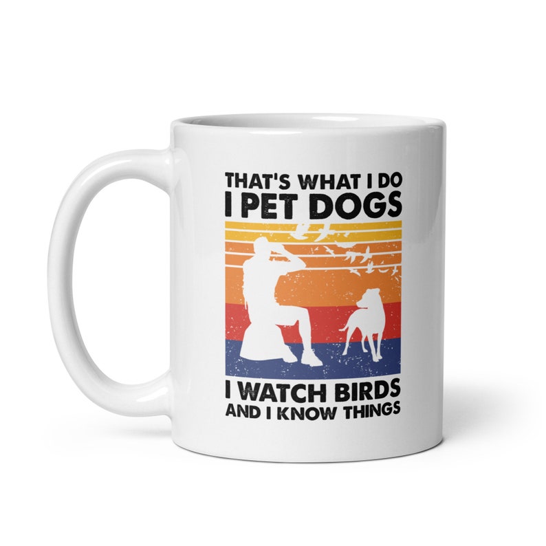 K&ouml;nnte beinhalten: Wei&szlig;e Keramik-Kaffeetasse mit Retro-Design. Die Tasse zeigt eine Silhouette einer Person, die V&ouml;gel beobachtet, mit einem Hund an ihrer Seite. Der Text lautet "That's what I do I pet dogs I watch birds and I know things."