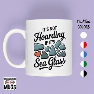 May include: White ceramic mug with the text "IT'S NOT Hoarding IF IT'S Sea Glass" in black script. The design includes sea glass illustrations in shades of blue, orange, and gray. The mug has a white handle and the brand name "TheReallyNice MUGS" is at the bottom.