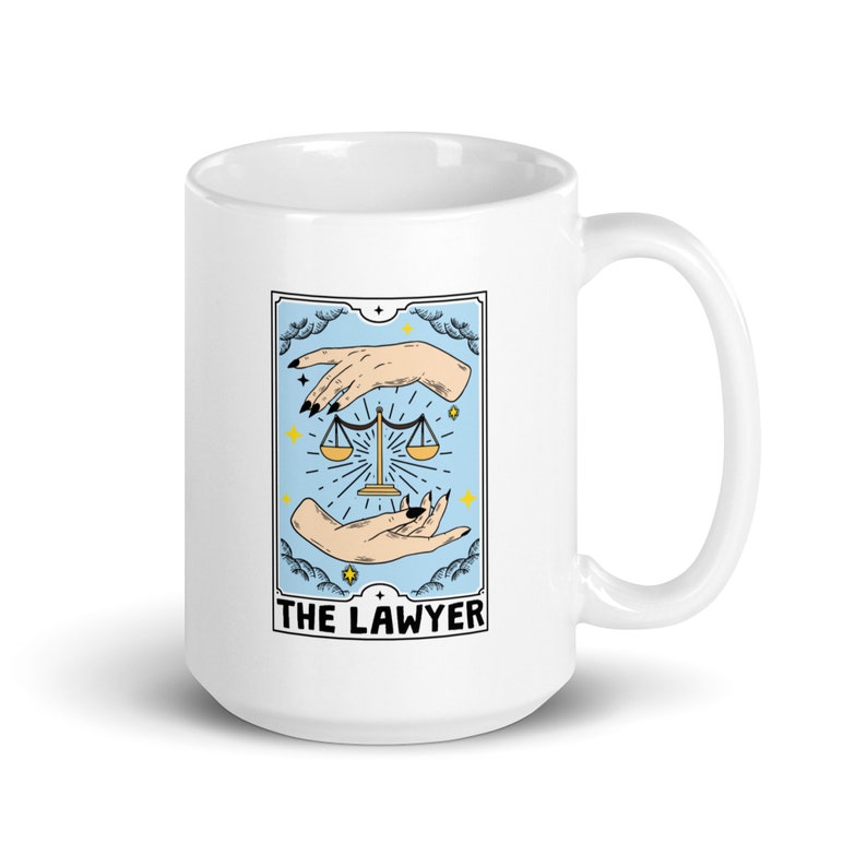 May include: White ceramic mug with a tarot card design featuring a blue background, two hands holding a scale, and the text "THE LAWYER".
