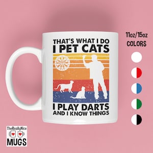 May include: White ceramic mug with a retro design featuring a person playing darts and two cats. The text reads "That's what I do I pet cats I play darts and I know things".