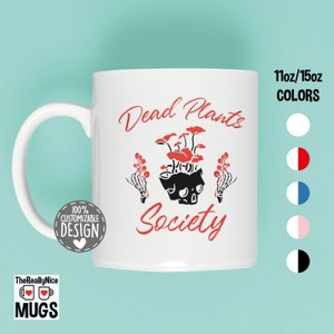 May include: White ceramic mug with a black and red design. The mug features a skull with mushrooms growing out of the top and the text "Dead Plants Society".