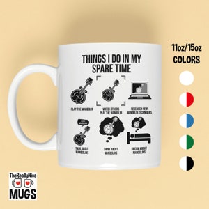 May include: White ceramic mug with a black and white design that says "Things I do in my spare time". The design includes illustrations of a mandolin, a computer, and a sleeping person. The mug is available in 11oz or 15oz sizes and in a variety of colors.